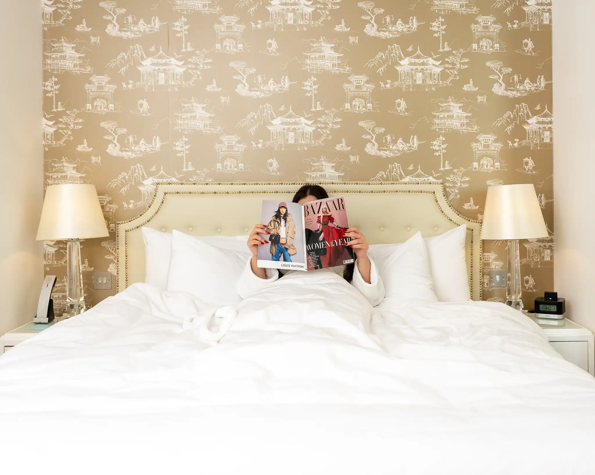 A girl reading a magazine on bed.