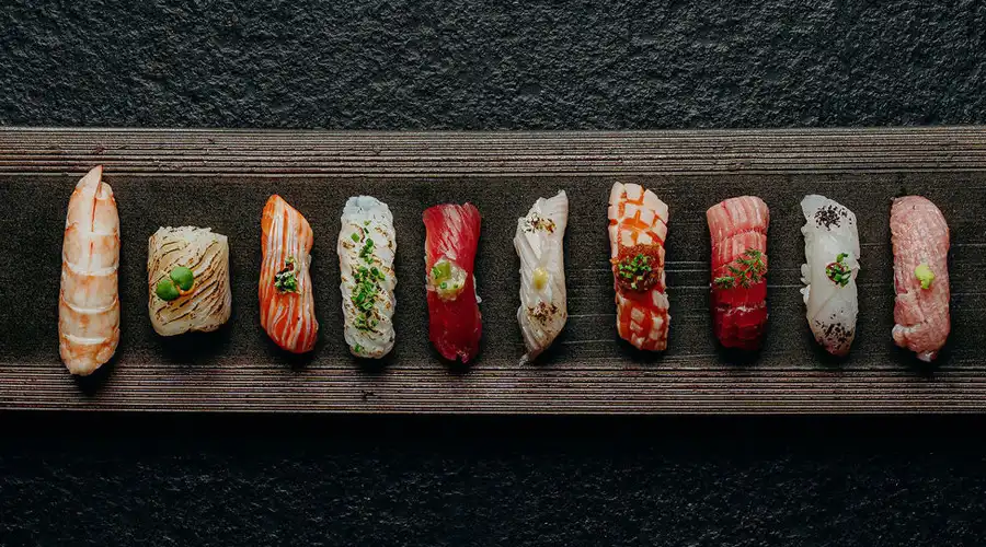 Overhead view of assorted nigiri sushi on a rectangular wooden platter served at Kiyomi.