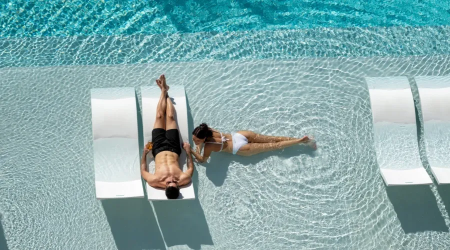 A man and woman relaxing on daybeds at Isoletto Pool at Dorsett Gold Coast
