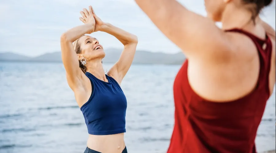 Two women in yoga poses along beach