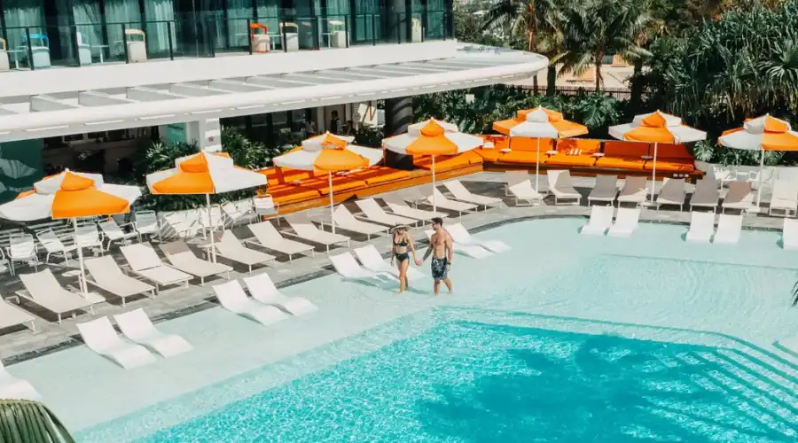 Couple walking besides rooftop pool and orange umbrellas at Dorsett Gold Coast