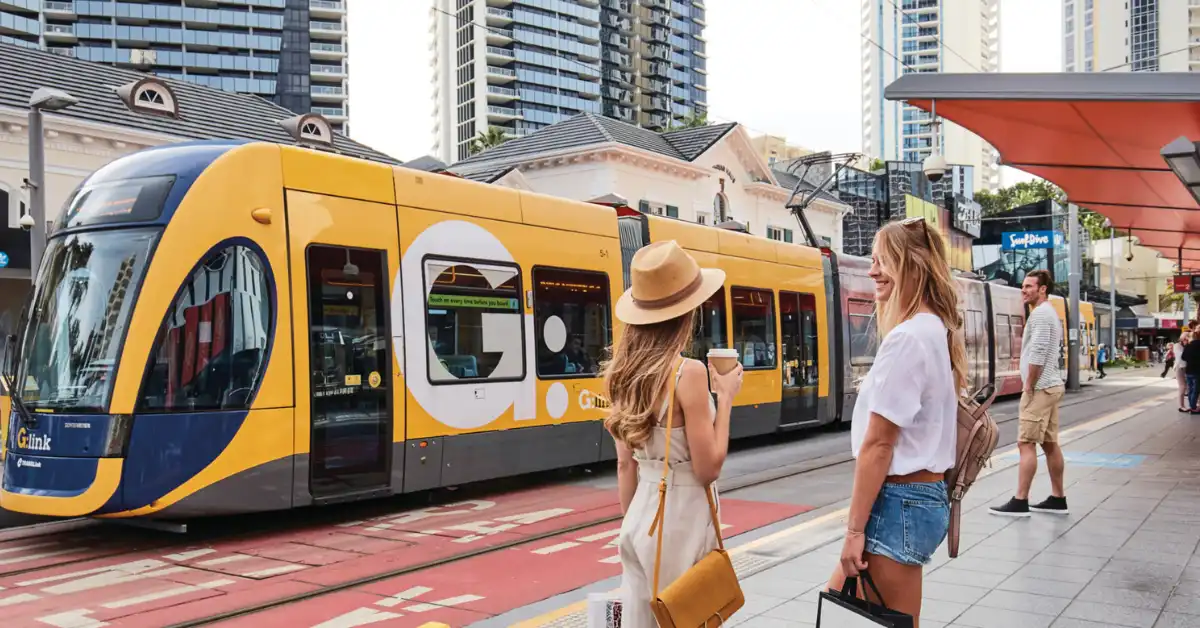 People wait at a Gold Coast G:link stop as a light rail goes past