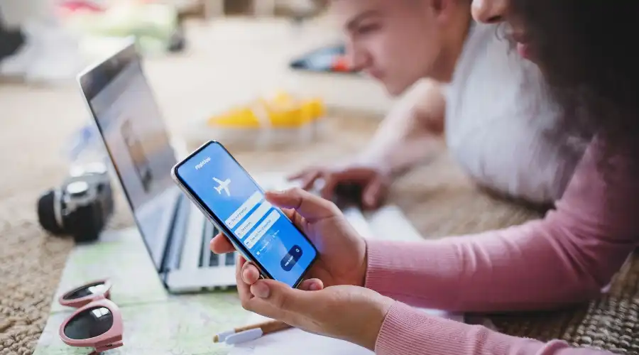 Two people planning a trip on a laptop and smartphone