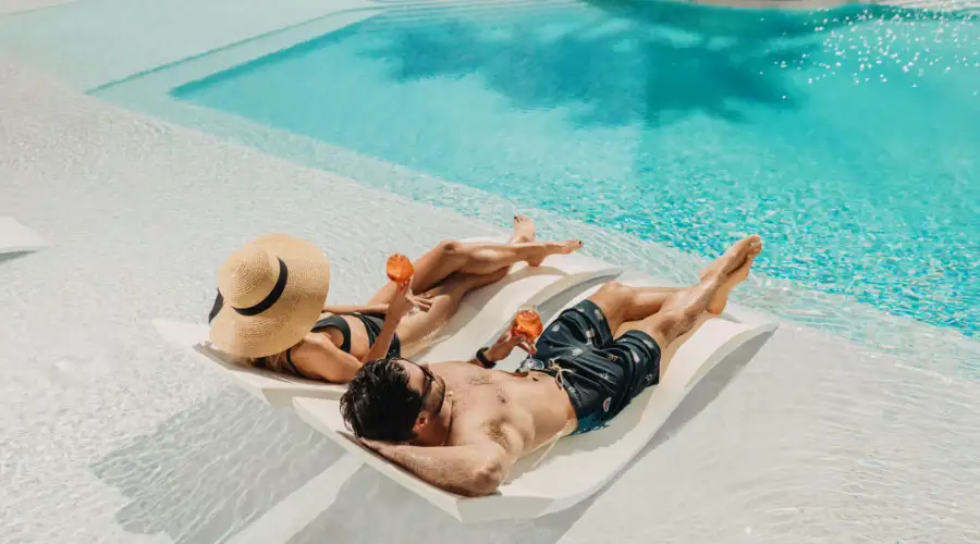 Couple lounging by Isoletto Pool with orange cocktails in hand
