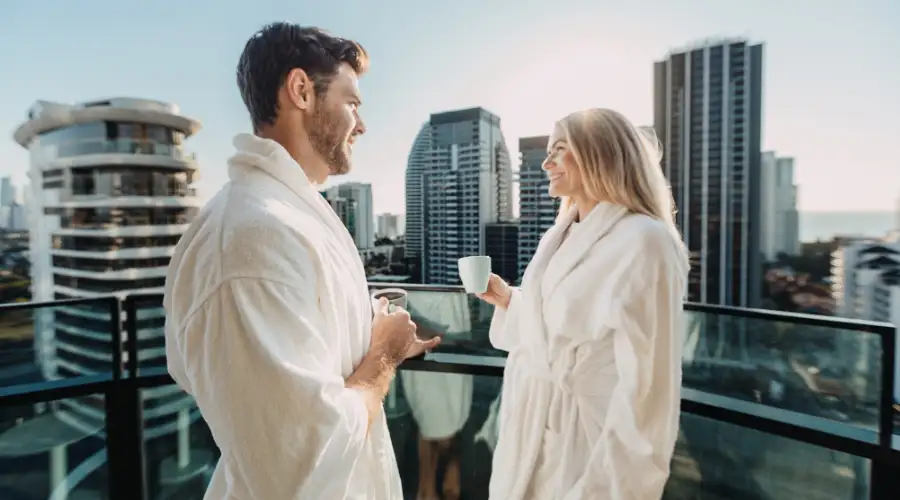 Couple in white bathrobes sipping on coffee overlooking the sunrise