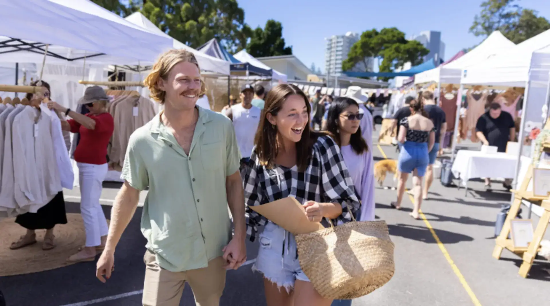 A couple walk hand in hand at a local market in Burleigh Heads