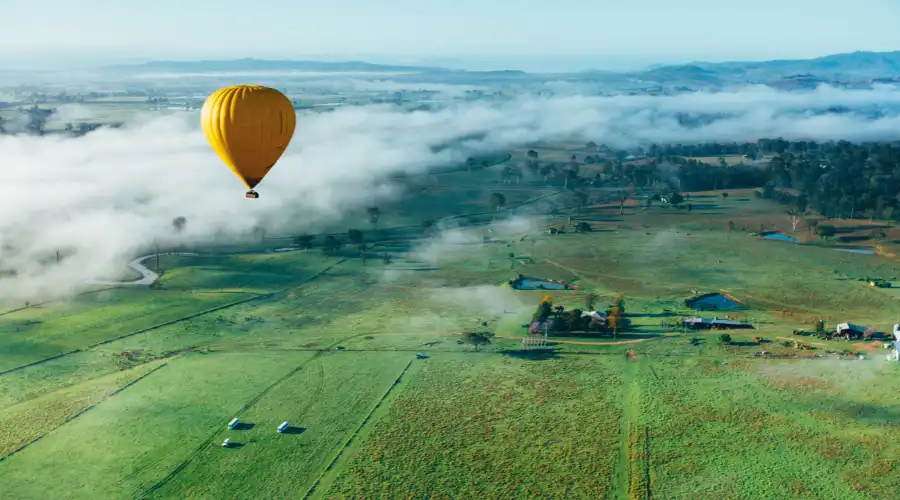Yellow hot air balloon soaring over the hinterlands in QLD