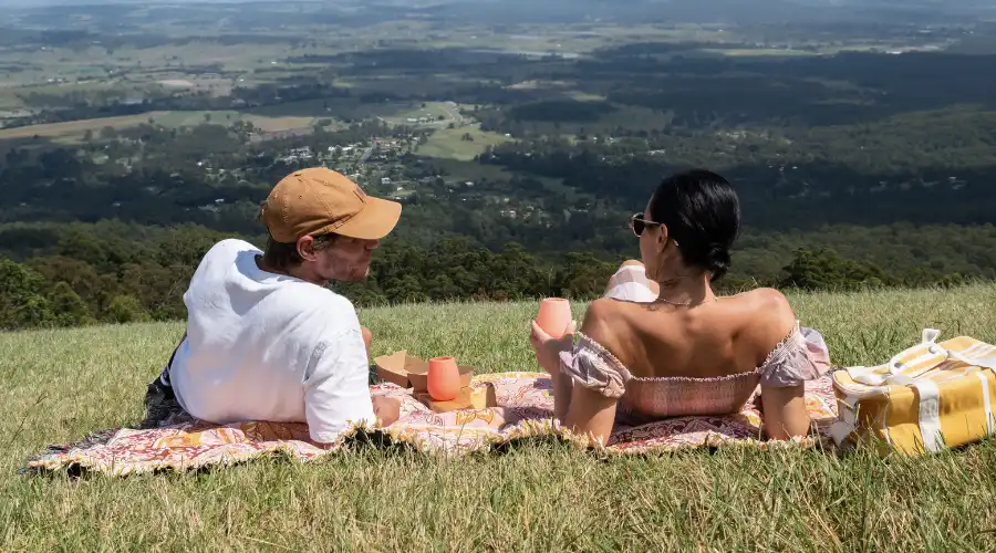 Couple enjoying a picnic on the grass, looking out over the valley at Tamborine Mountain
