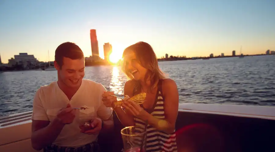 Couple smiling over drinks and dessert on sunset cruise 