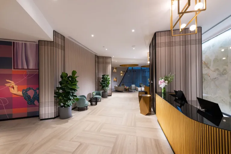 Image of a hotel lobby with two staff on the front desk and a big mural on the left