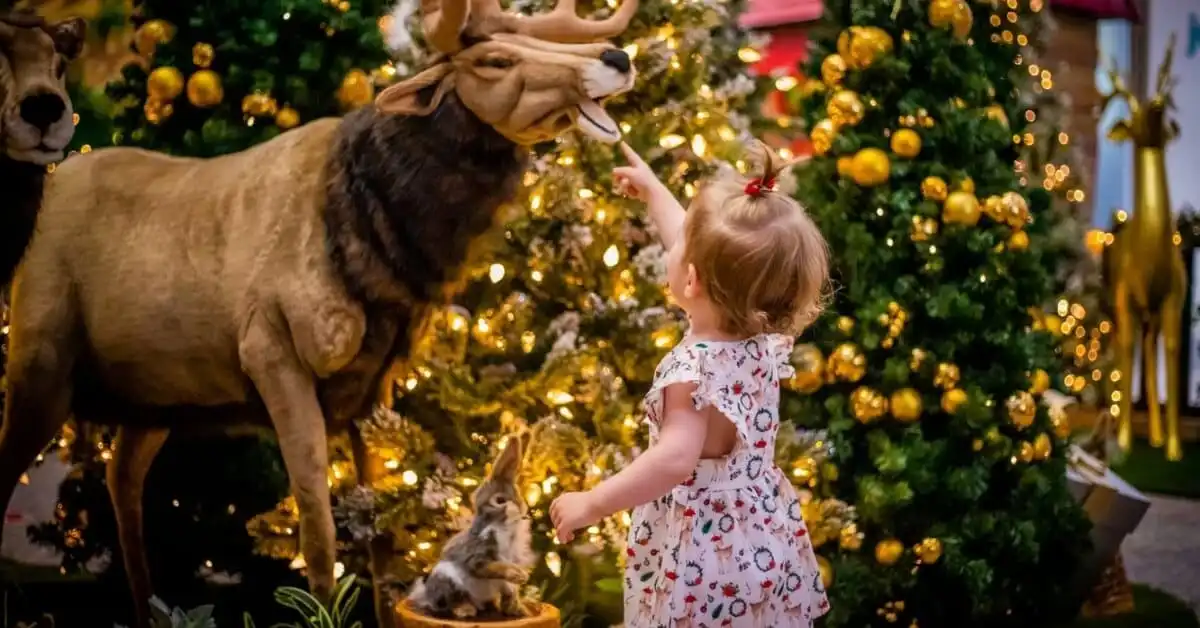 A toddler touches a reindeer statue at the Melbourne Christmas Wonderland