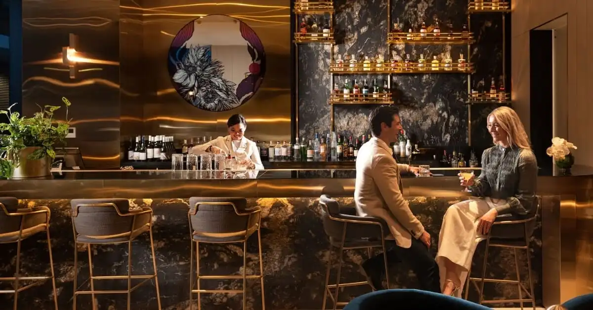 Jin Bar's chic interior featuring a bartender crafting drinks behind a stylish bar with gold accents.