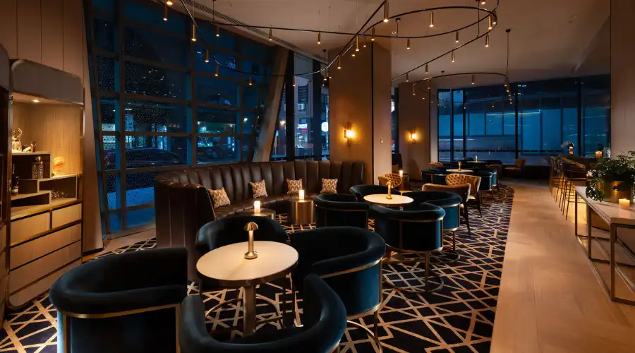 Modern lounge bar interior with velvet chairs, round tables, and warm pendant lighting in Dorsett Melbourne