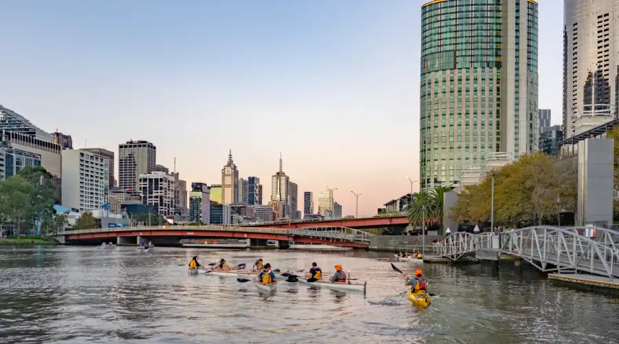 Kayakers on the Yarra River at sunset with Melbourne CBD in background
