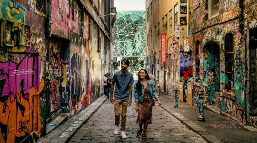 Couple walking through Melbourne laneway art