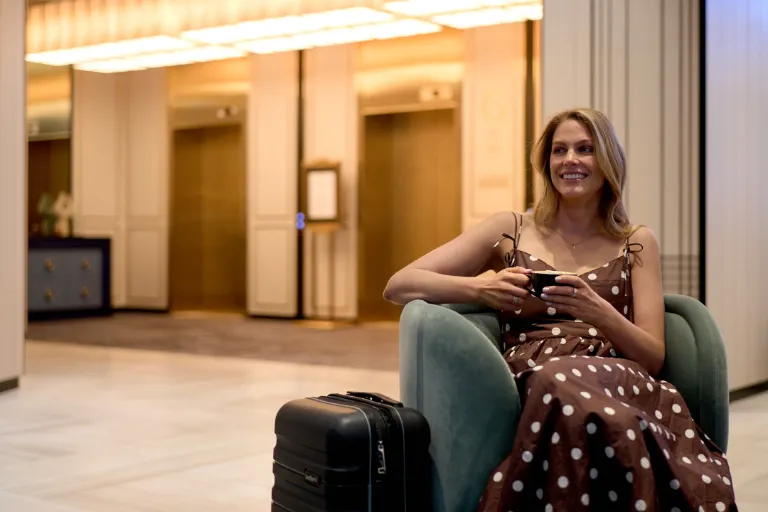 A lady holding a coffee cup in a bright hotel lobby