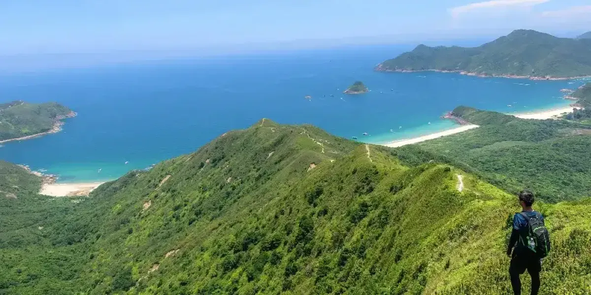 Hiker overlooking lush green hills and bays along the Lantau Peak Hong Kong