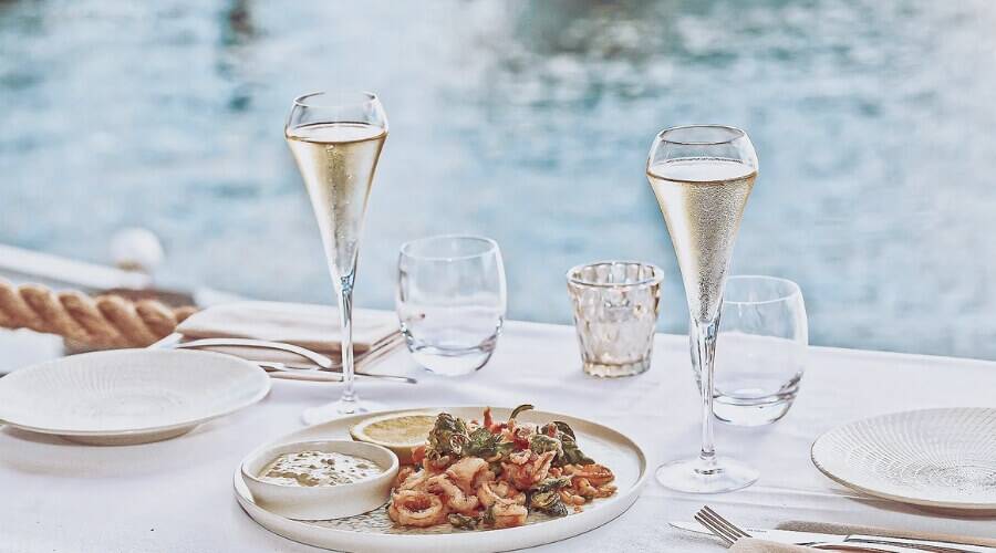Champagne glasses and seafood on a waterside restaurant table