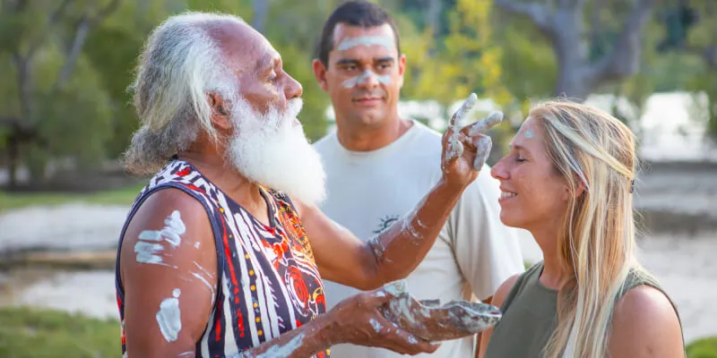 Aboriginal man applying paint to woman's face