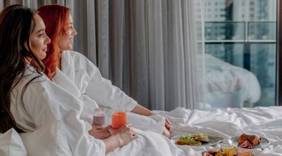 Two women enjoying breakfast in bed at Dorsett Gold Coast