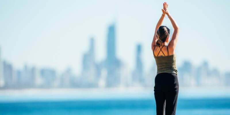 Woman doing yoga at Burleigh Heads with City Backdrop