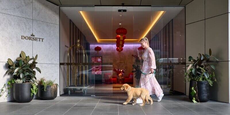 Woman walking her dog into the Dorsett Melbourne lobby